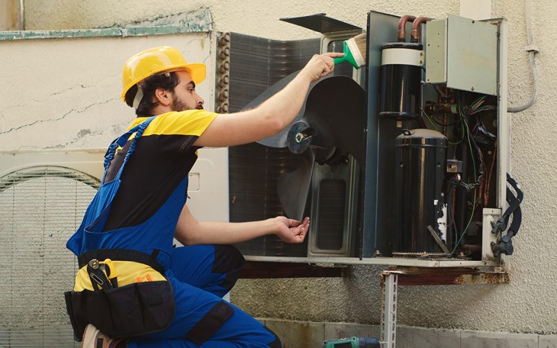 Skilled HVAC engineer removing layer of dust from blower fan to prevent ventilation system damage. Precise mechanic cleaning internal parts to stop risk of condenser overheating